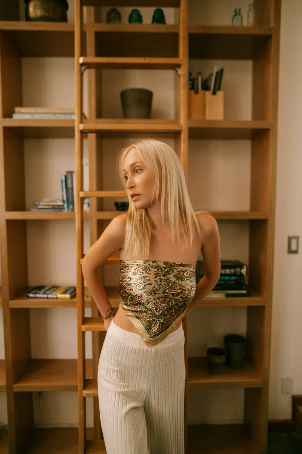 a woman posing in front of a book shelf