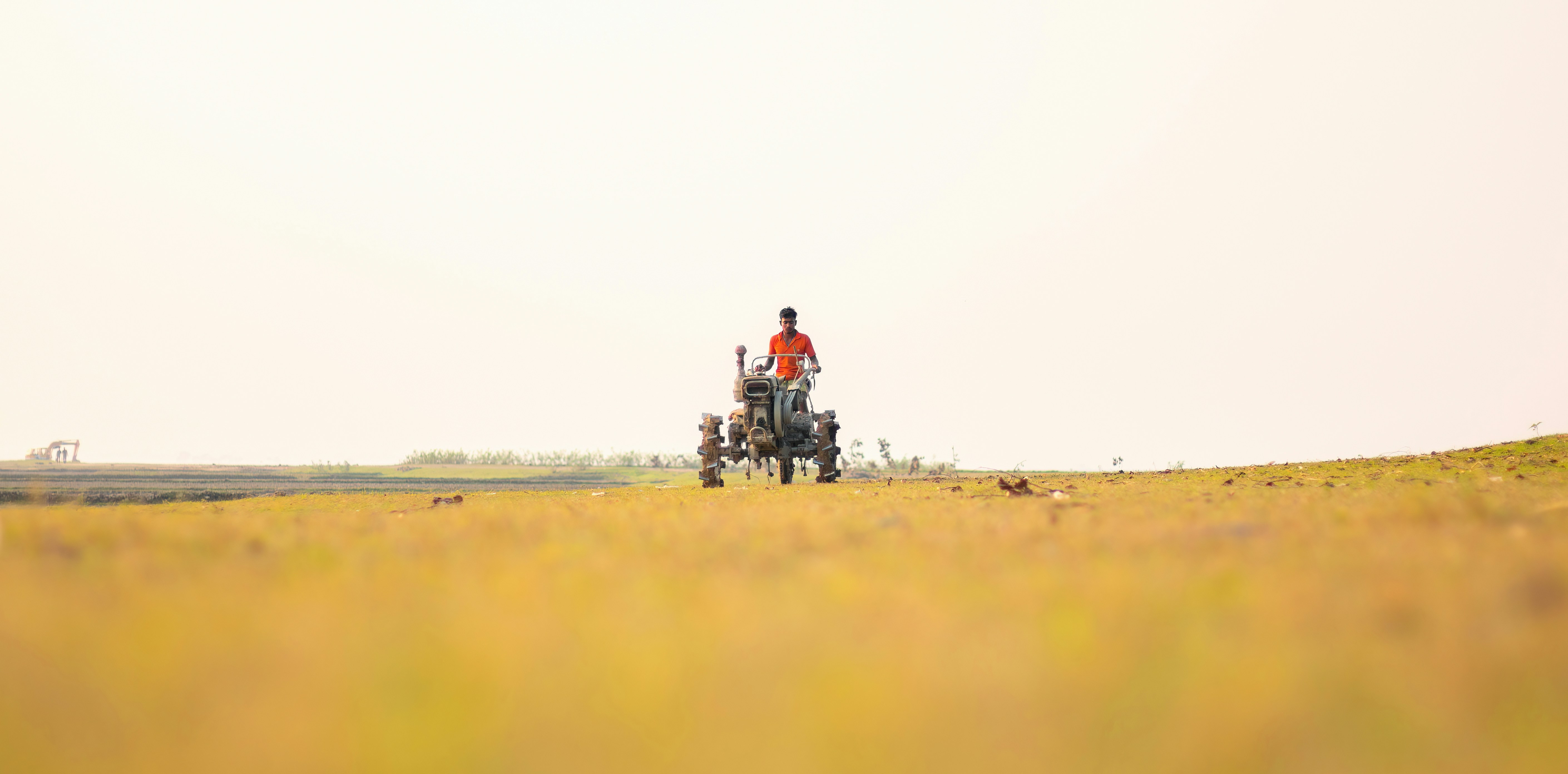 A farmer driving a compact tractor on a small farm