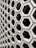 A hexagonal pattern of concrete blocks arranged in a grid, creating a uniform and structured appearance. The blocks have hollow centers and shadowed interiors, giving a sense of depth and dimension.
