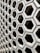 A hexagonal pattern of concrete blocks arranged in a grid, creating a uniform and structured appearance. The blocks have hollow centers and shadowed interiors, giving a sense of depth and dimension.