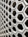A hexagonal pattern of concrete blocks arranged in a grid, creating a uniform and structured appearance. The blocks have hollow centers and shadowed interiors, giving a sense of depth and dimension.