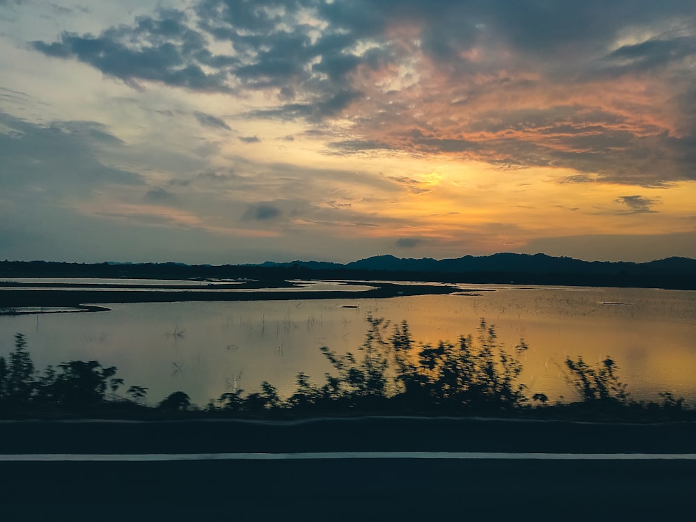 a lake with trees and a sunset