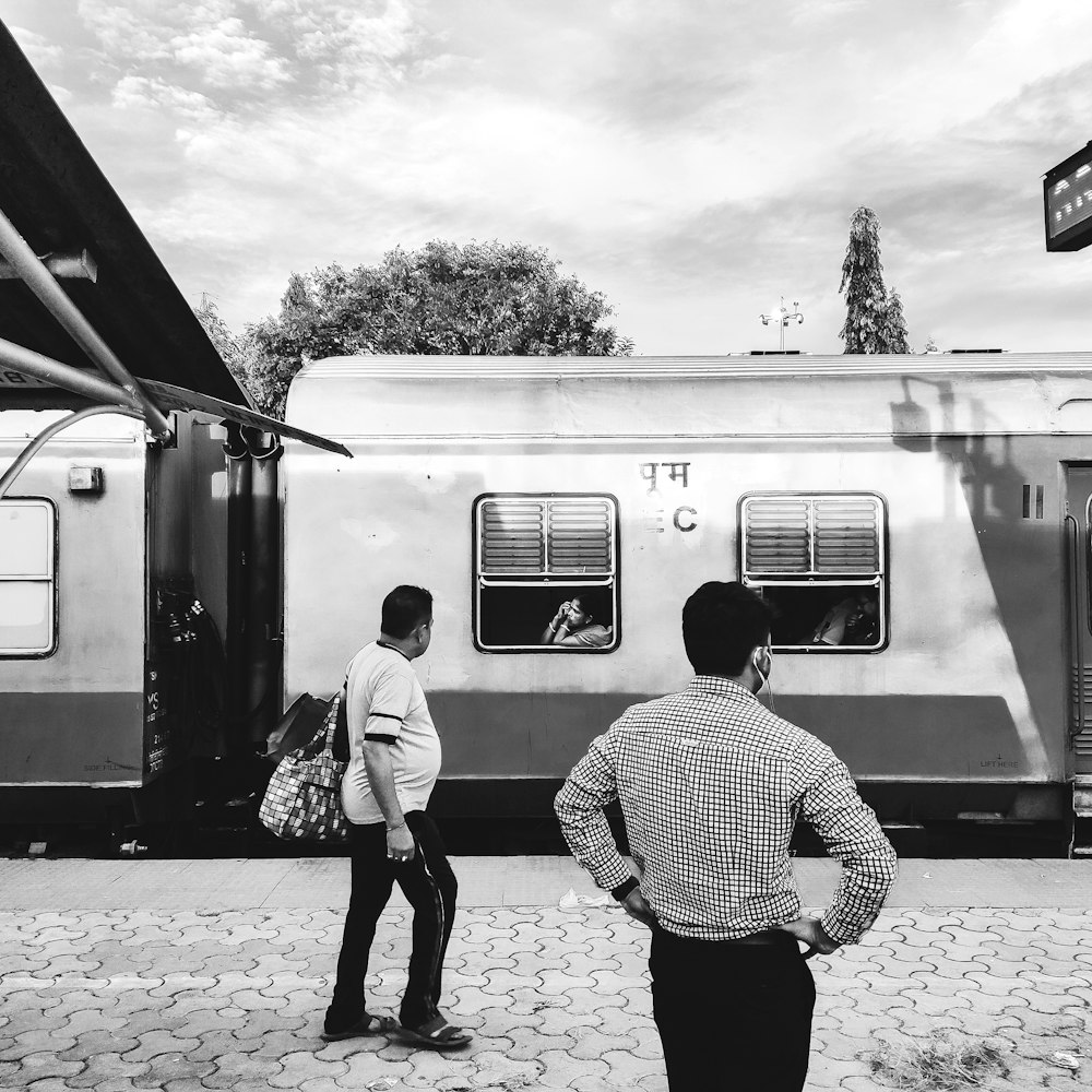 a couple of people stand near a train