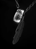 Silver pendant shaped like a raven perched on a twisted branch, photographed with dramatic shadows.
