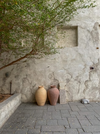 a couple of vases sit on a brick surface