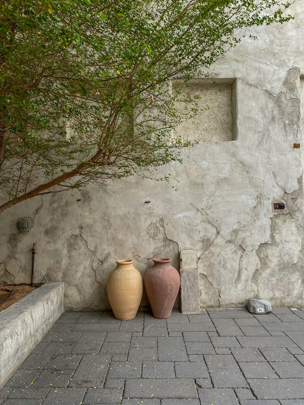 a couple of vases sit on a brick surface