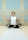 A person is seated cross-legged on a yoga mat, performing a meditation pose with closed eyes. The background features an elegant wall with teal panels and gold borders.