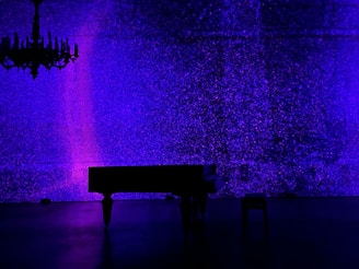 An artistic shot of colorful musical notes swirling around a grand piano in a dimly lit room.