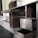 A partially assembled wooden cabinet with several open drawers and compartments, designed with a modern aesthetic. The cabinet features a sleek, dark wood finish combined with metallic elements, and is situated in a room with steps leading to another area.