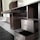 A partially assembled wooden cabinet with several open drawers and compartments, designed with a modern aesthetic. The cabinet features a sleek, dark wood finish combined with metallic elements, and is situated in a room with steps leading to another area.