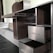A partially assembled wooden cabinet with several open drawers and compartments, designed with a modern aesthetic. The cabinet features a sleek, dark wood finish combined with metallic elements, and is situated in a room with steps leading to another area.