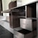 A partially assembled wooden cabinet with several open drawers and compartments, designed with a modern aesthetic. The cabinet features a sleek, dark wood finish combined with metallic elements, and is situated in a room with steps leading to another area.