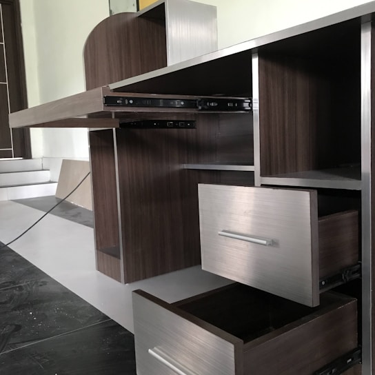 A skilled installer fitting sleek laminate cabinets in a modern hotel guest room.