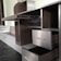 A partially assembled wooden cabinet with several open drawers and compartments, designed with a modern aesthetic. The cabinet features a sleek, dark wood finish combined with metallic elements, and is situated in a room with steps leading to another area.