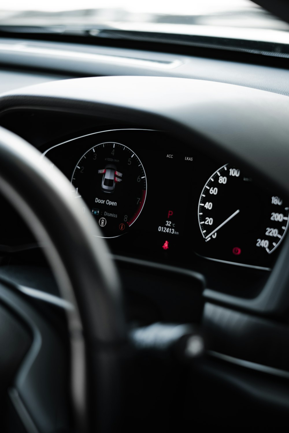 a car dashboard with a black steering wheel and a black dashboard