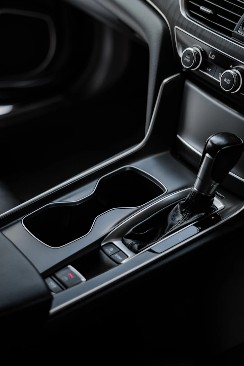 A spotless car center console with empty cupholders, shifter and climate dials, no dust in any seam.
