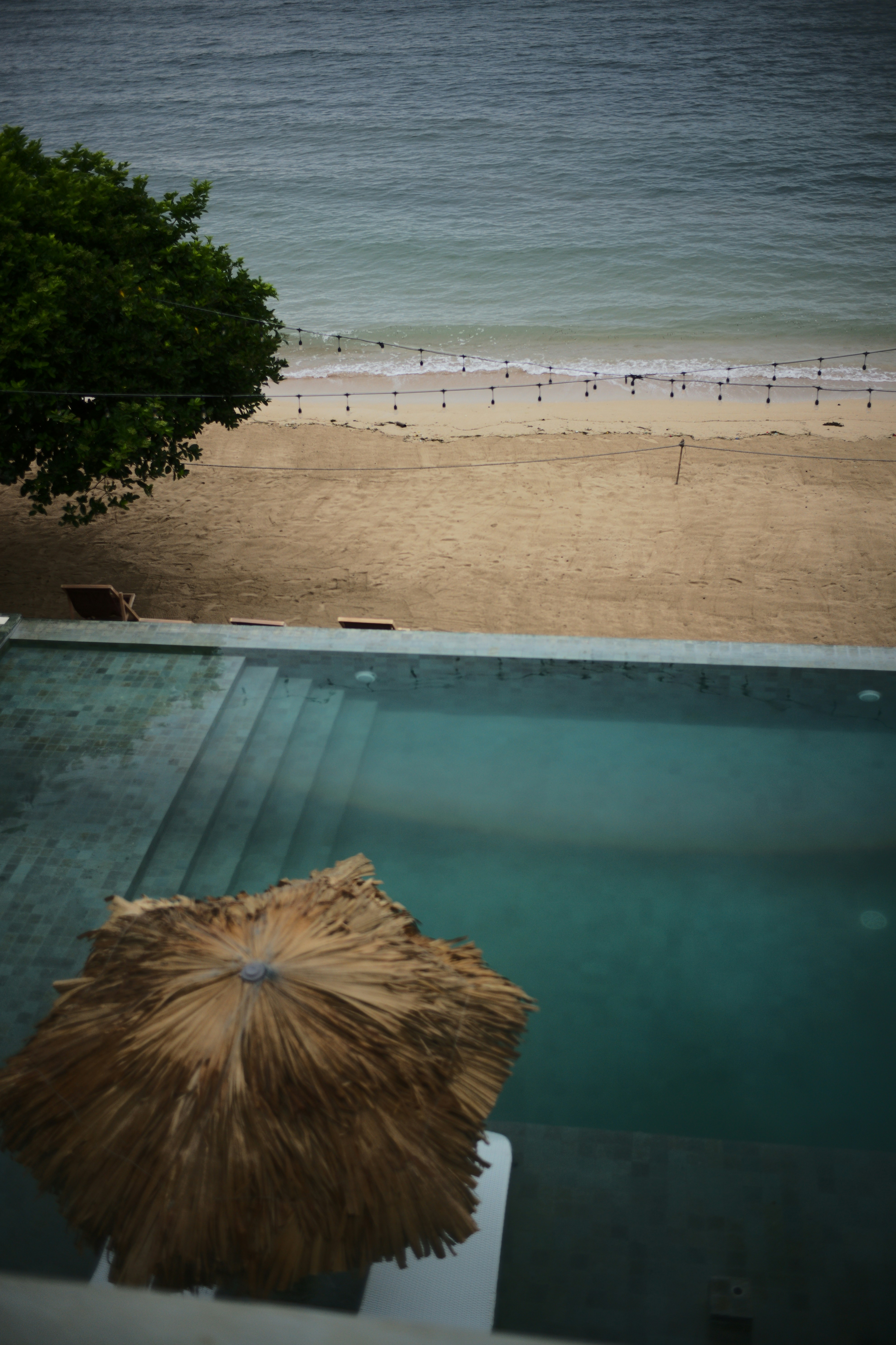 a beach with a pool and umbrella