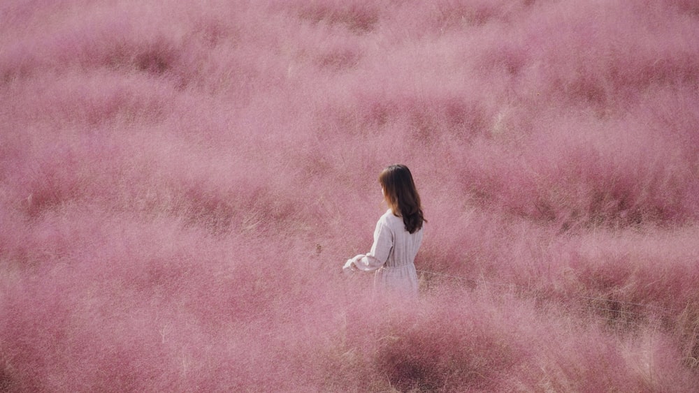 a person standing in a field of pink flowers