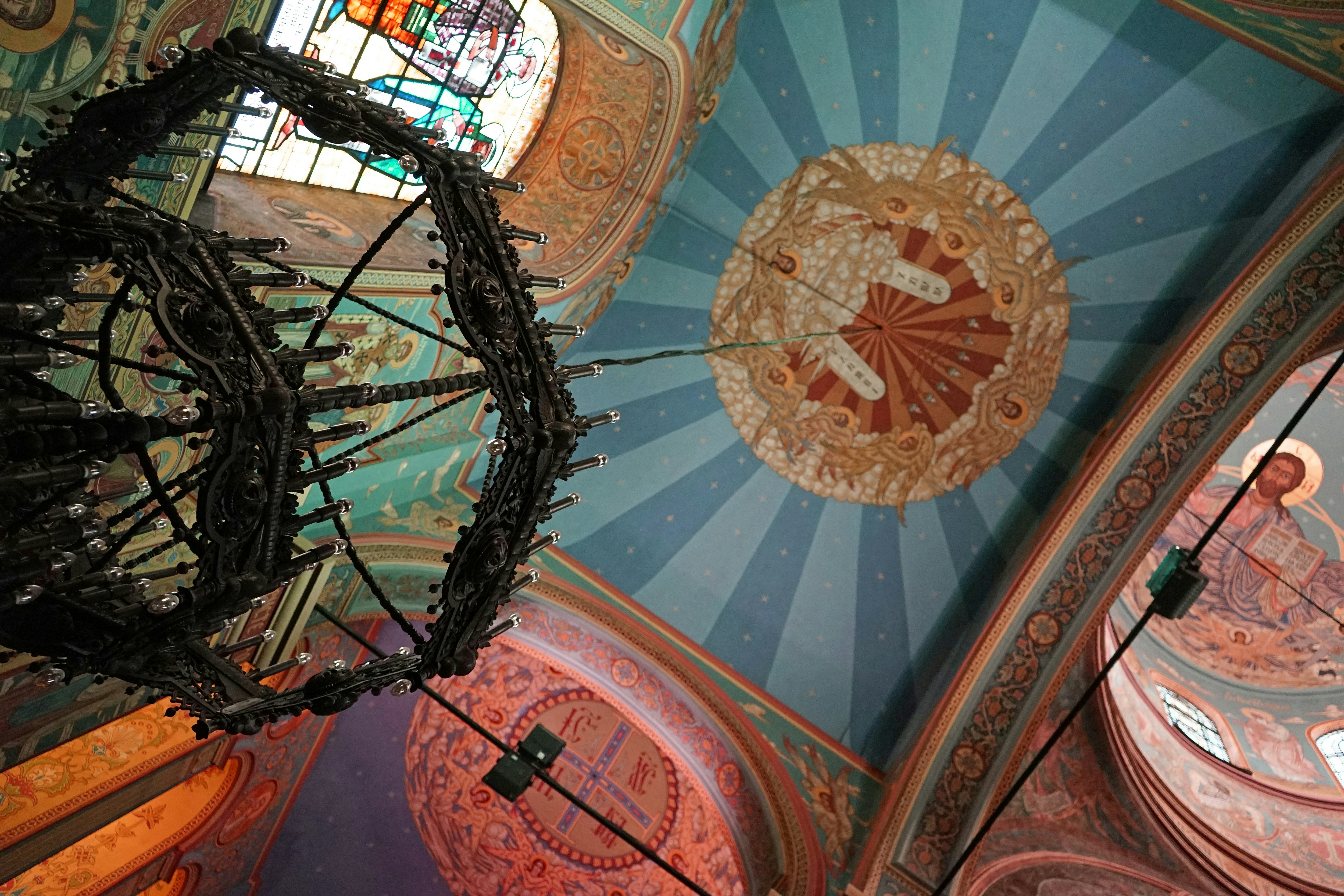 a circular ceiling with a circular design, The Dormition of the Mother of God Cathedral is the largest church building in Varna and the third largest cathedral in Bulgaria. Angled view on the beautiful icon painting in colored lighting.