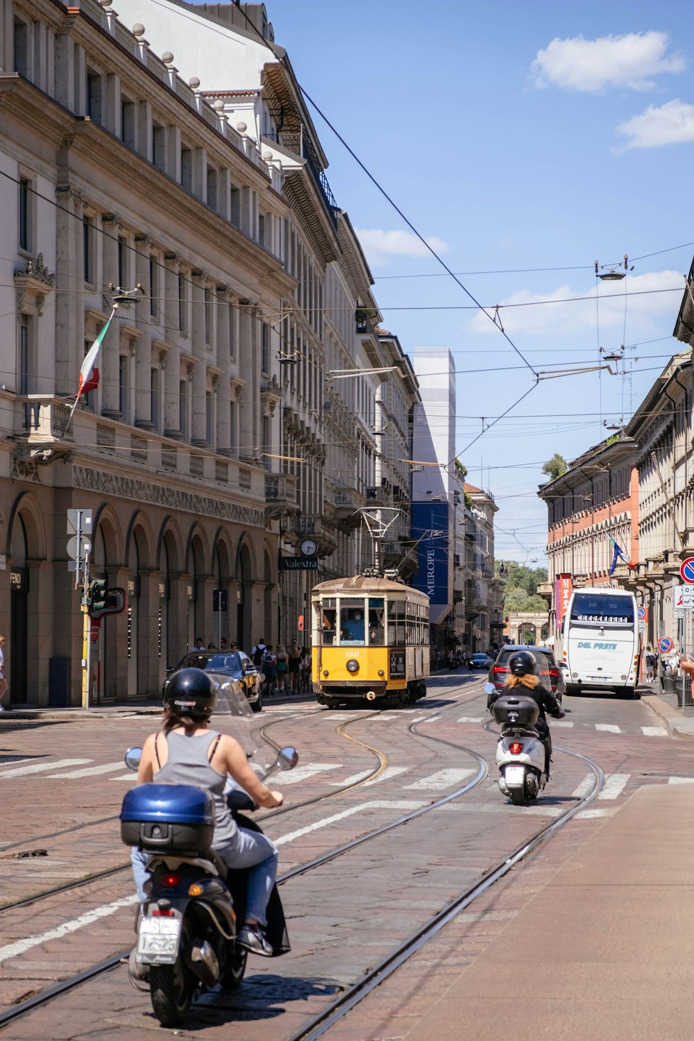 a person riding a motorcycle down a street with a trolley and cars