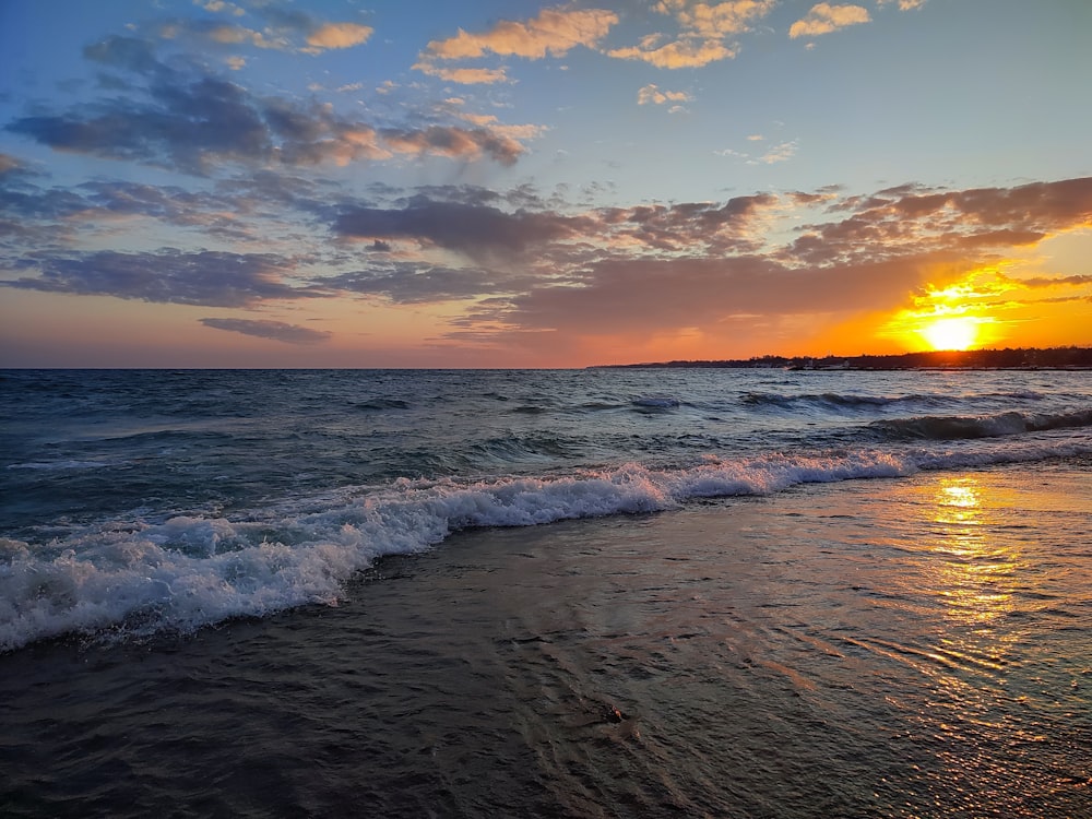 a beach with waves and a sunset