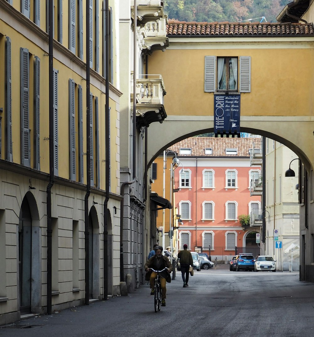 a person riding a bicycle on a street between buildings