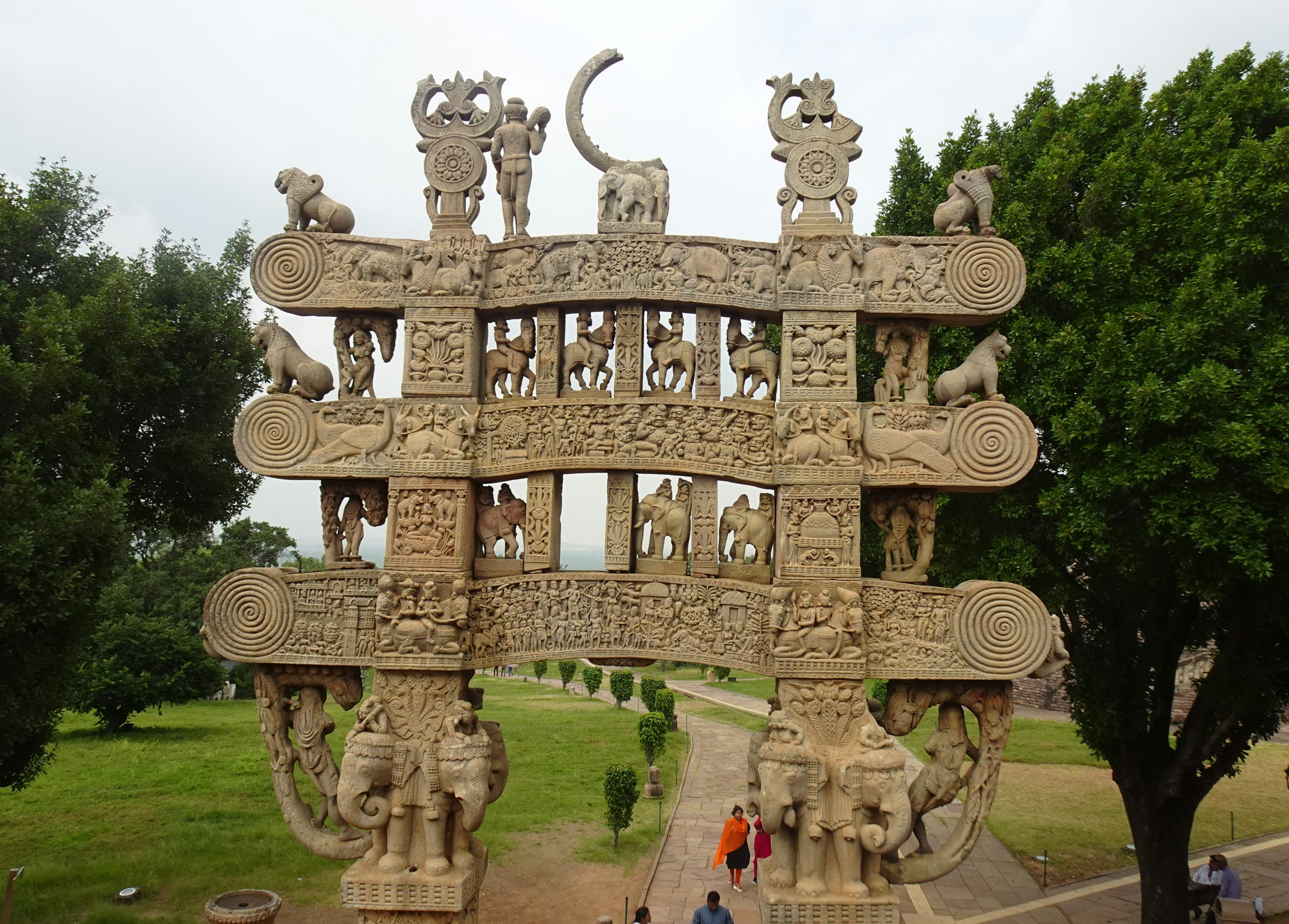 a stone structure with carvings with Sanchi in the background