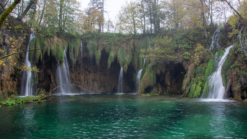 um corpo de água com cachoeiras e árvores ao seu redor