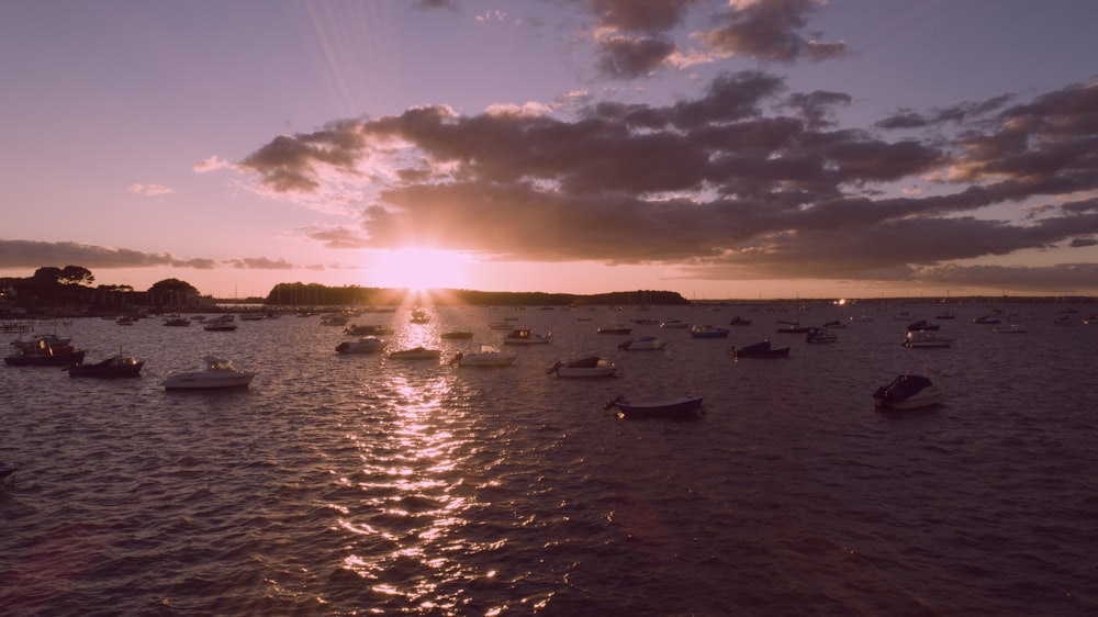ein Gewässer mit Booten darin und einem Sonnenuntergang im Hintergrund