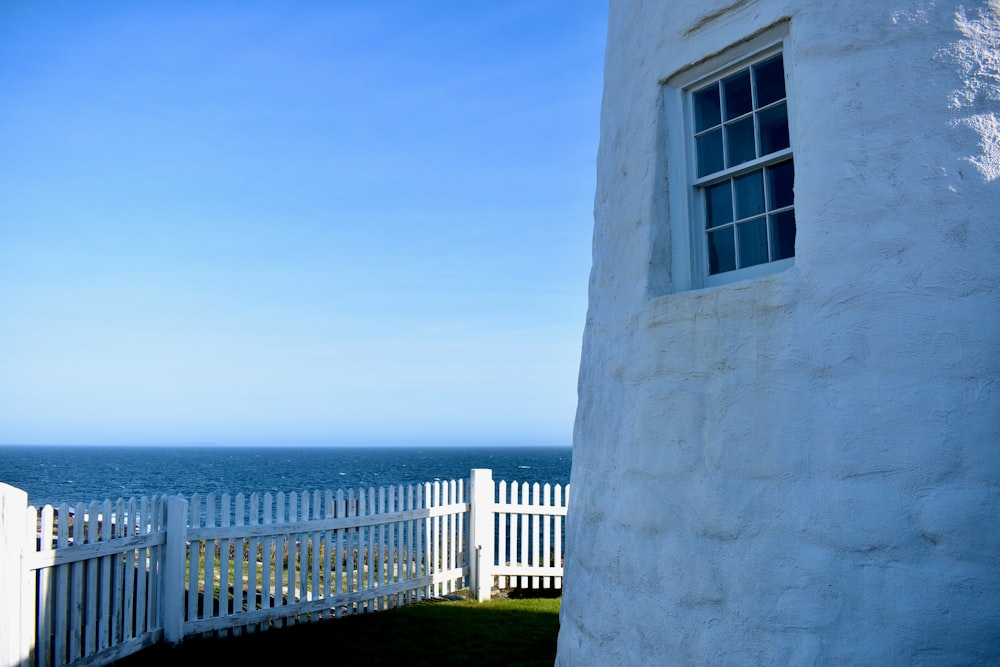 a white building with a white railing and a body of water in the background