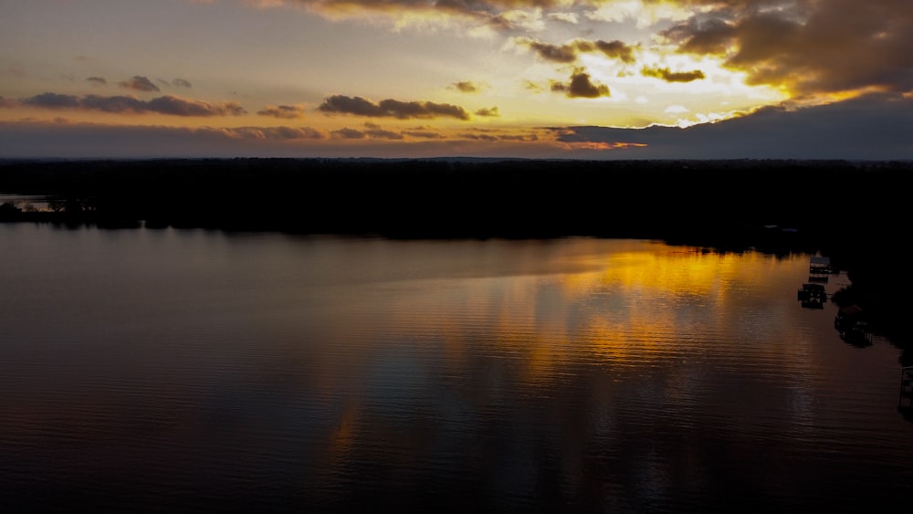 uno specchio d'acqua con una barca dentro e un tramonto sullo sfondo
