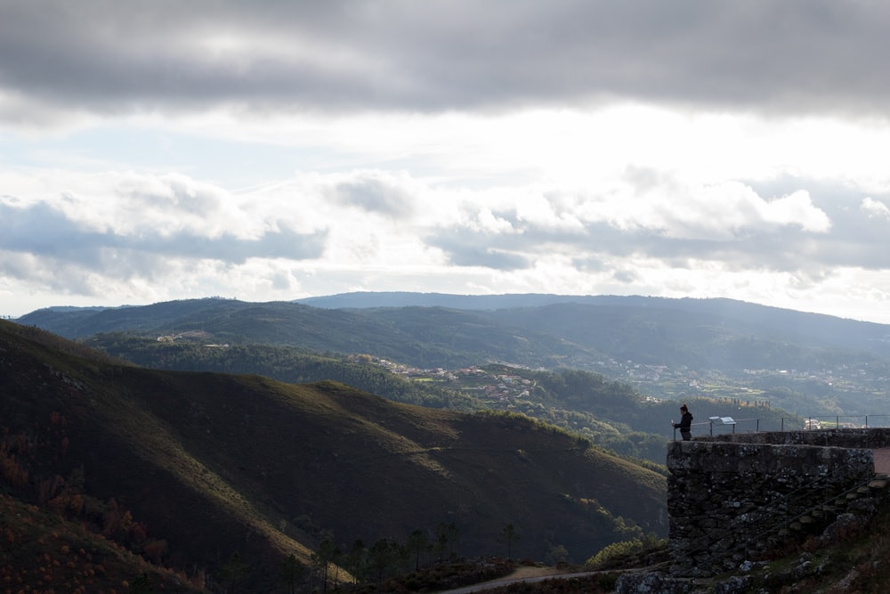 a person standing on a ledge overlooking a valley