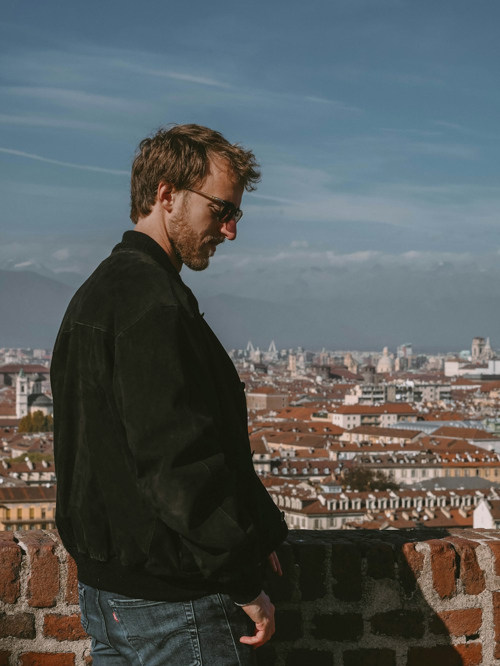 a man standing on a ledge overlooking a city