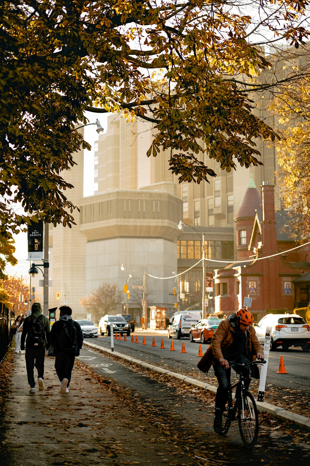 a man riding a bicycle on a street with people walking on the sidewalk