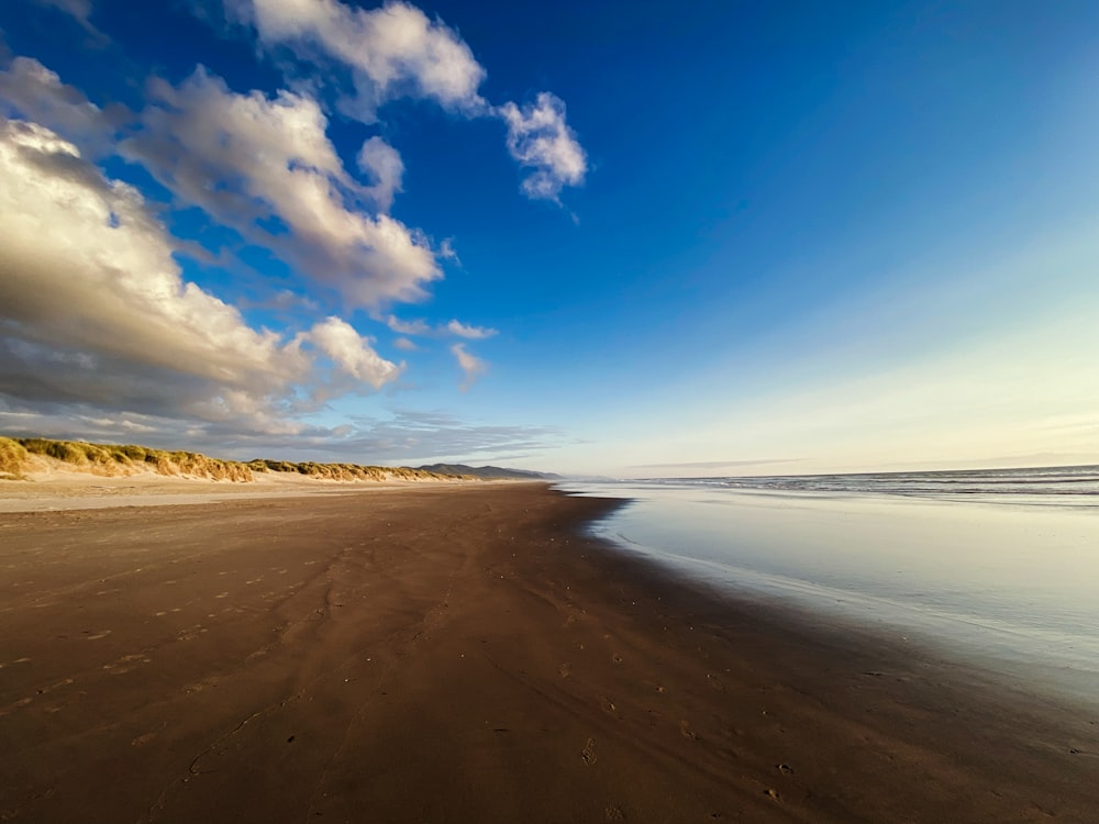 a sandy beach with blue sky and clouds