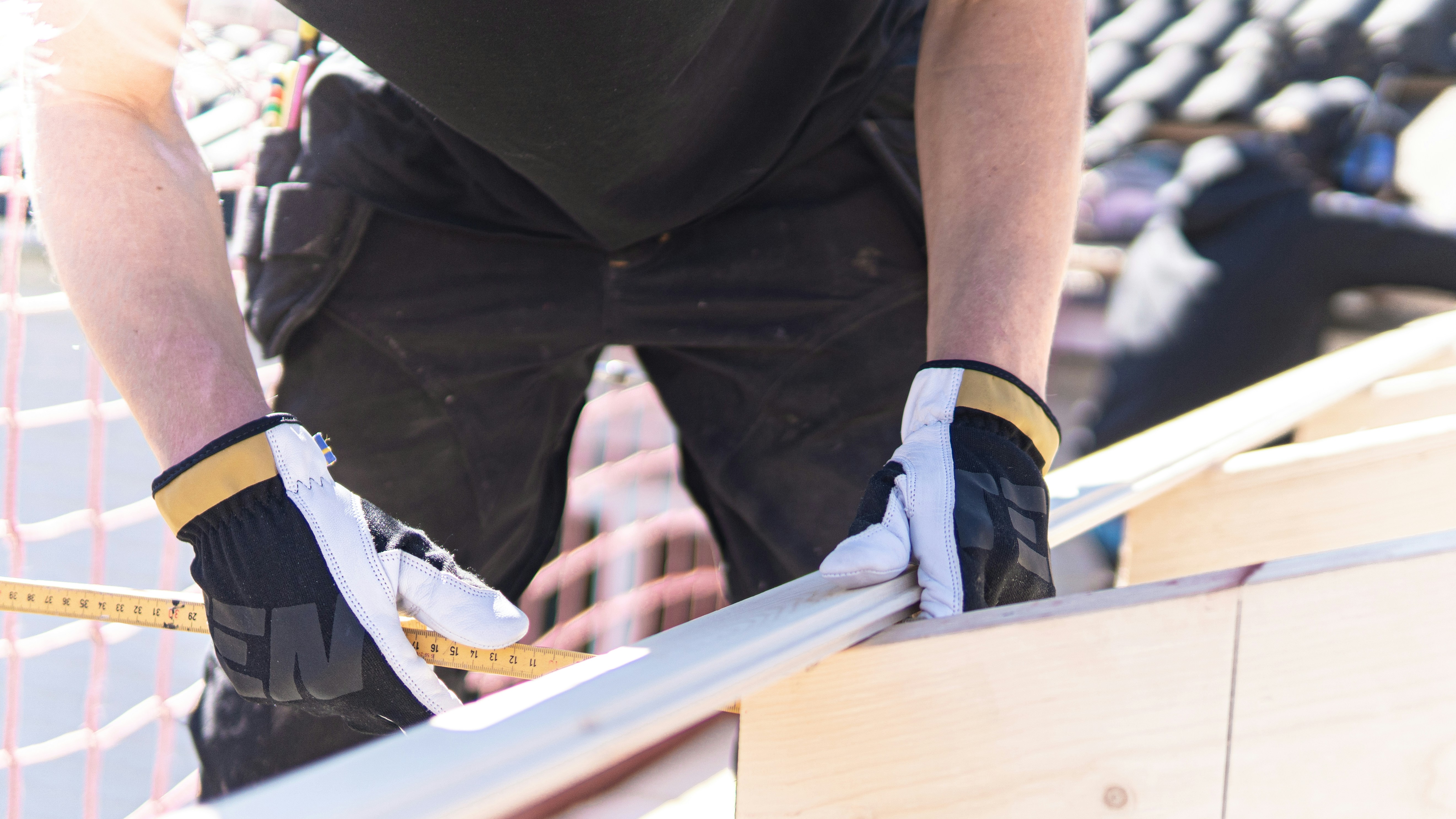 Carpenter building a house using working gloves from Ten Protection.
