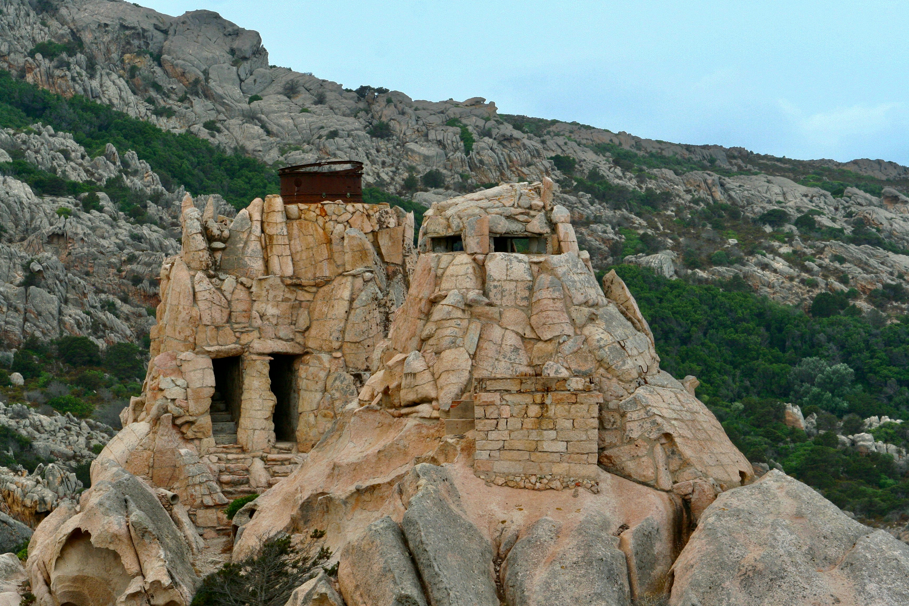 Foto Una estructura de piedra en una colina rocosa – Imagen Batteria di ...