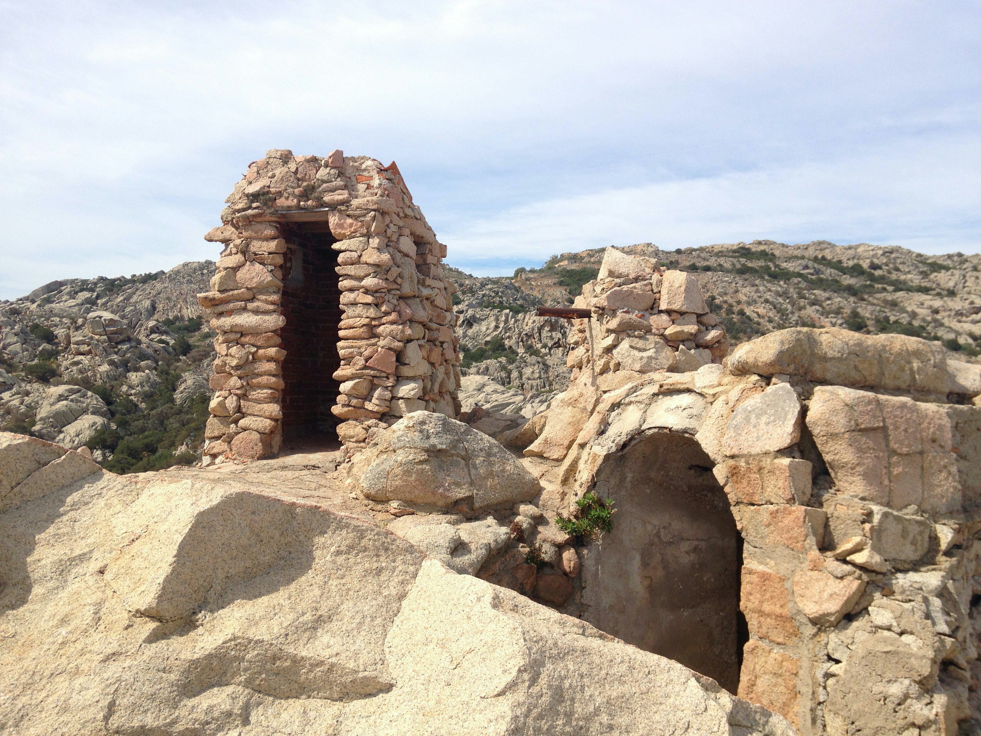 a stone building in the desert, Walking into "The National Park of the Maddalena Archipelago" In Caprera island if you follow the footpath # 11, after 35 minutes of walking, you reach the old fortification called "Antonio CANDEO". Was built in 1928 as a medium battery to defend northeastern Caprera from ships. Simply amazing !