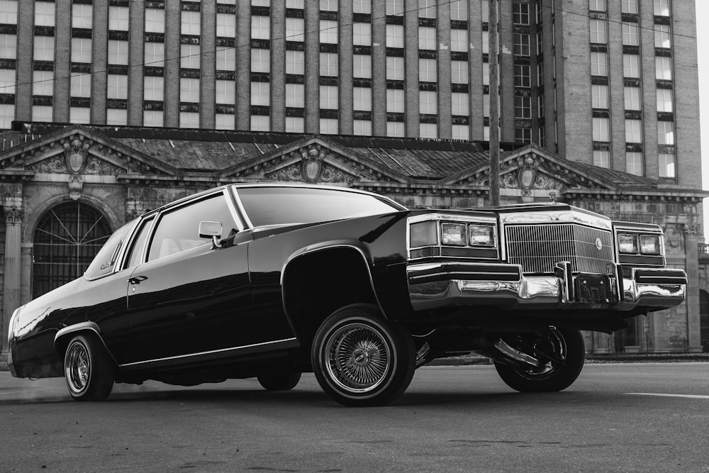 a black and white photo of a car parked in front of a building