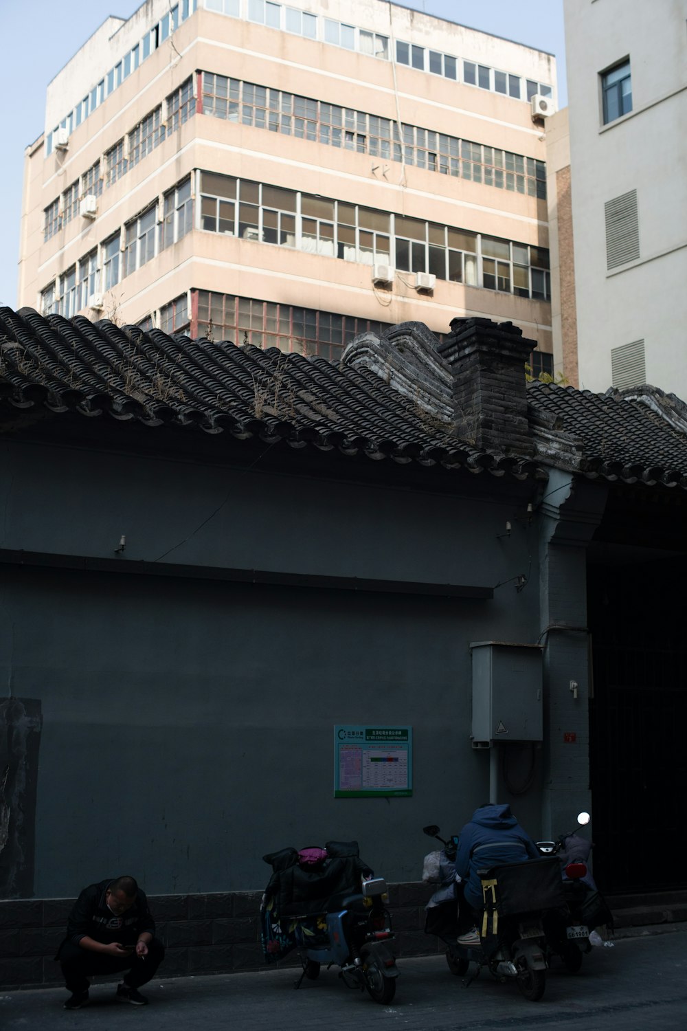 a person sitting on a sidewalk next to a building