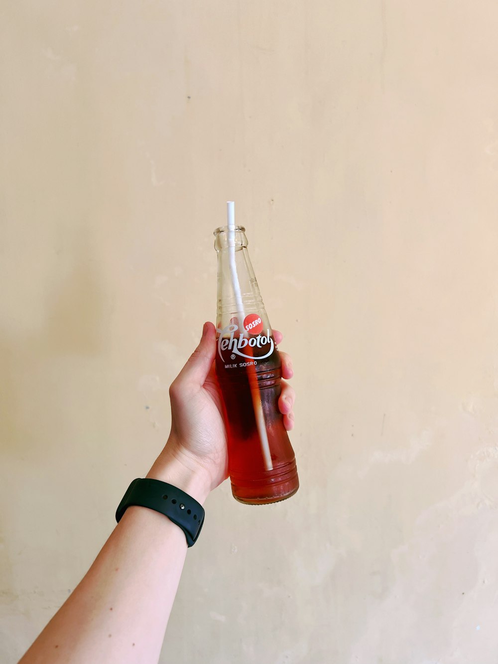 eine Hand, die eine Flasche Soda hält