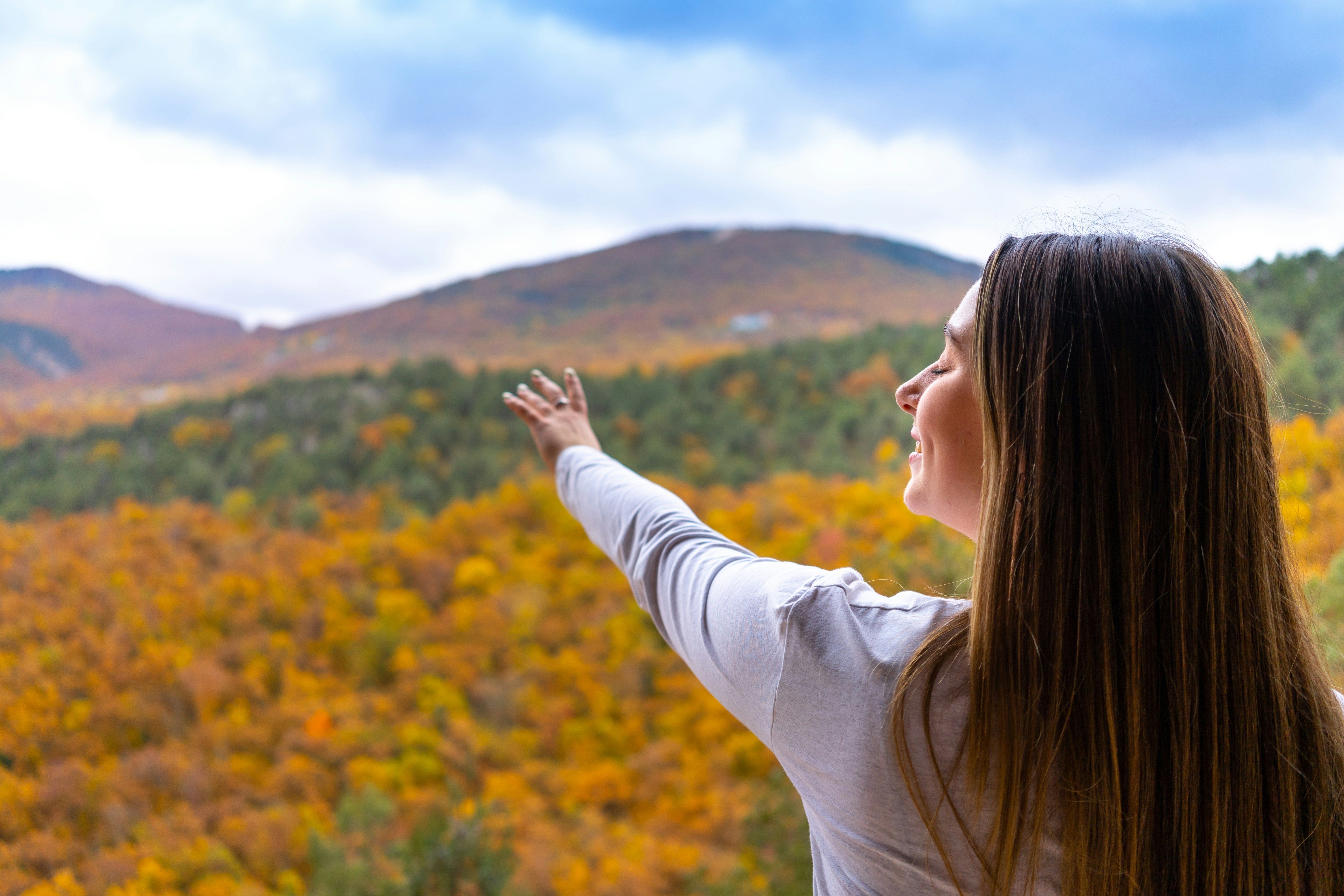 A young girl stretches out her hand and smiles against the backdrop of hills and autumn forest. Balaklava, Sevastopol, Baidarskaya valley, Murzak-koba. November 2022