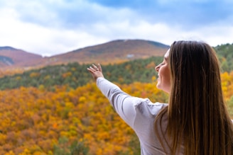 a person with the hand up in front of a field of yellow flowers