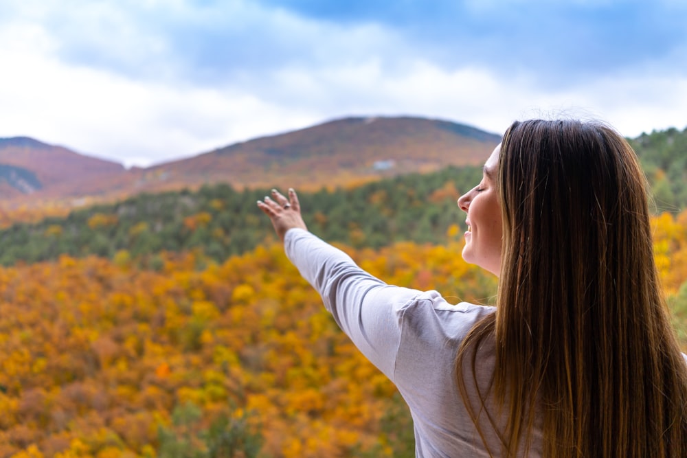 a person with the hand up in front of a field of yellow flowers