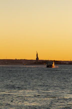 A friendly captain smiling aboard a sleek boat with NYC skyline in the background at sunset.