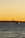 A smiling woman standing on the deck of a boat during sunset, with NYC skyline in the background