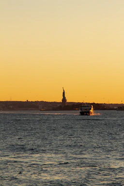 A friendly captain smiling aboard a sleek boat with NYC skyline in the background at sunset.