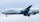 An aircraft featuring the Lufthansa airline logo is in flight, with its landing gear extended. The plane's body is mostly white, and it is flying against a backdrop of an overcast sky.