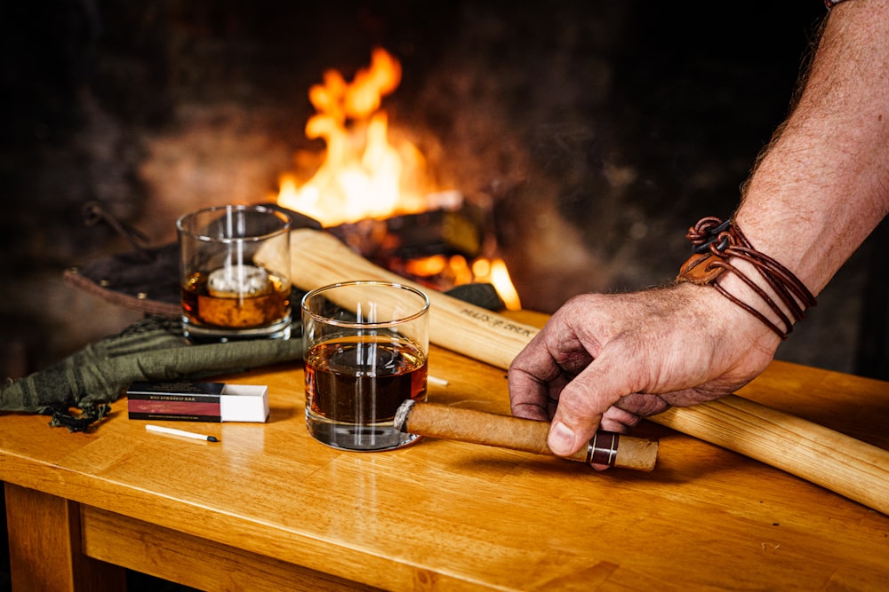 a hand holding a cigar over a burning wood table