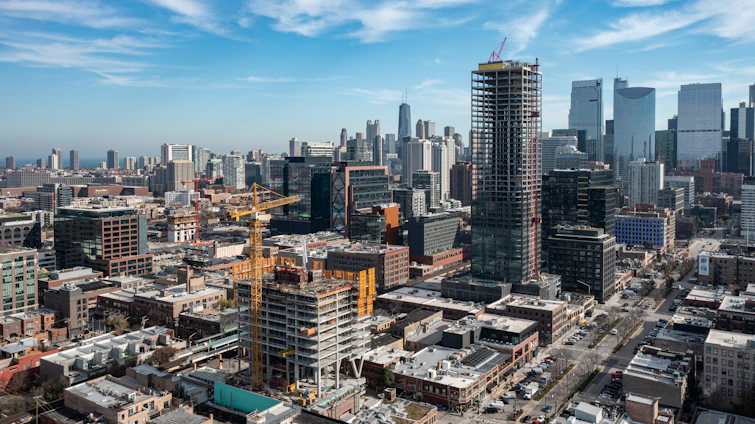 A professional woman reviewing construction plans on site with a city skyline in the background.